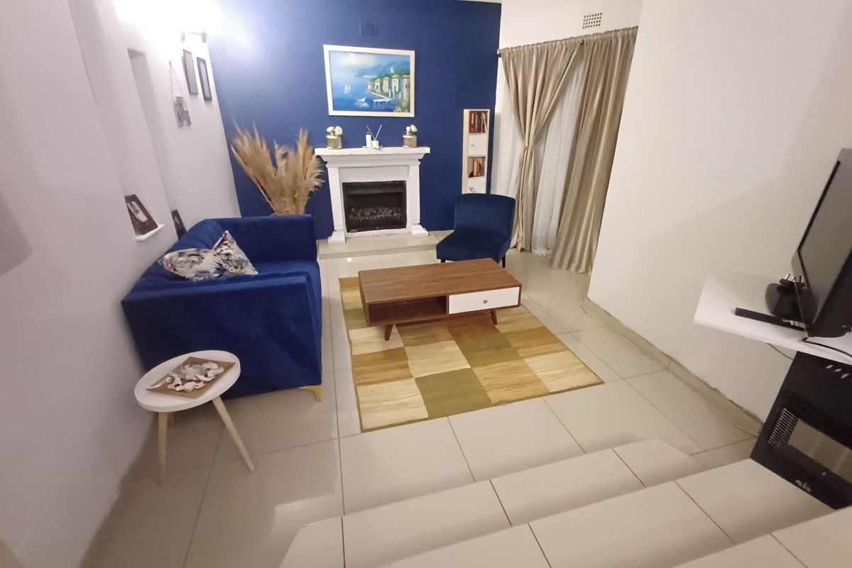 A cozy living room featuring a built-in fireplace, tiled flooring, and a striking blue accent wall, creating a warm and inviting atmosphere.