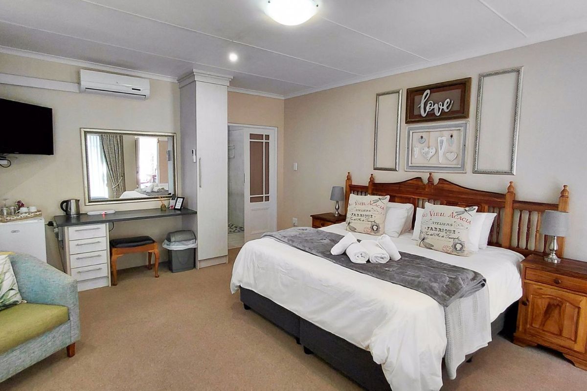 A well-maintained bedroom featuring a built-in wardrobe, wall-mounted air conditioning unit, and an en-suite bathroom access.