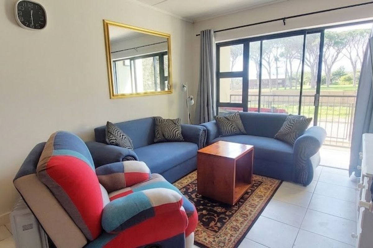 A comfortable living room featuring tiled flooring and large sliding glass doors that provide access to an outdoor balcony area.