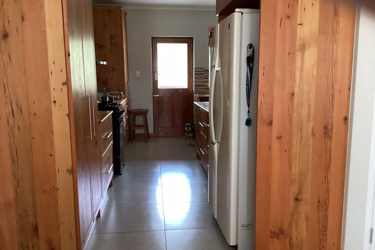 A galley-style kitchen featuring timber cabinetry, tiled flooring, and a rear exterior door providing natural light.