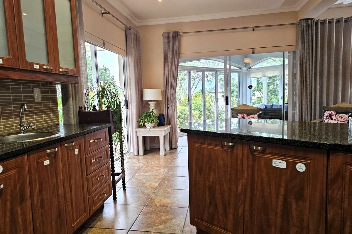 A kitchen featuring dark wood cabinetry, granite countertops, and tiled flooring, with large sliding doors providing access to an outdoor patio area.