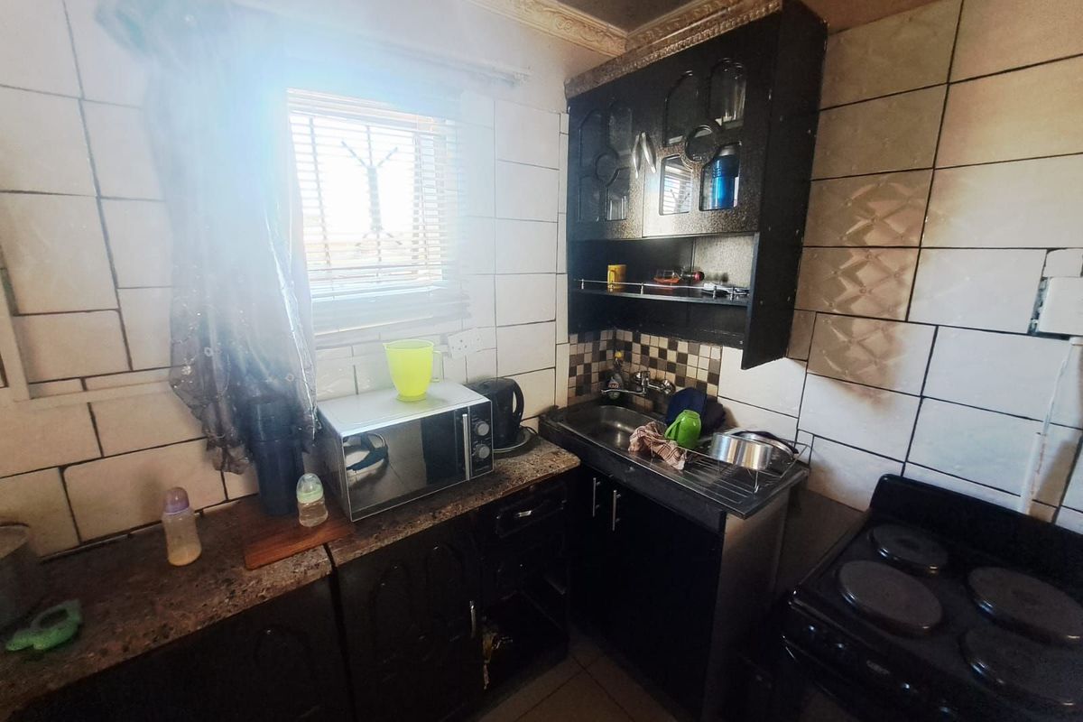 Compact kitchen featuring dark cabinetry, tiled walls, and a built-in sink, offering a functional prep area with natural light from the window.