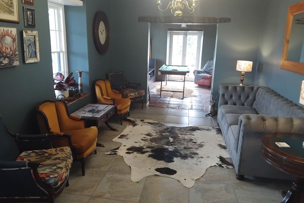 A spacious living room featuring tiled flooring, a decorative chandelier, and a transition area leading to an adjacent room with French doors.