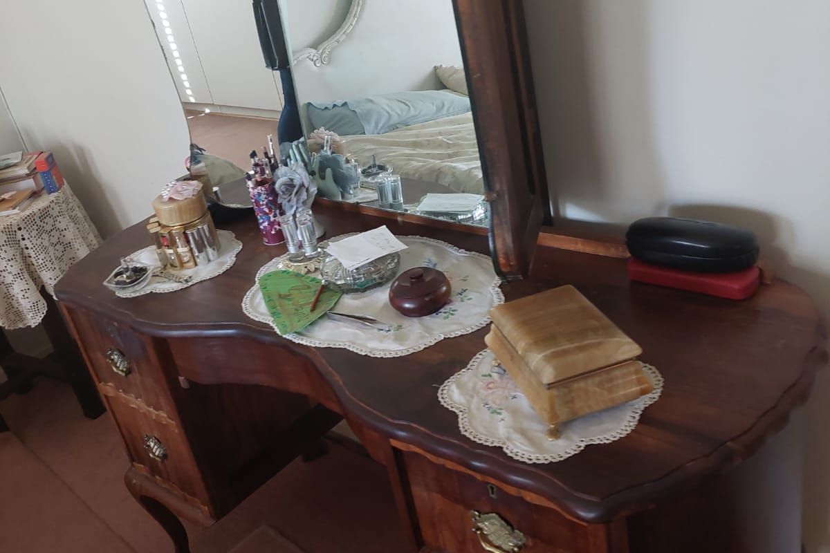 A bedroom featuring a classic wooden vanity table with a large mirror and built-in storage drawers.
