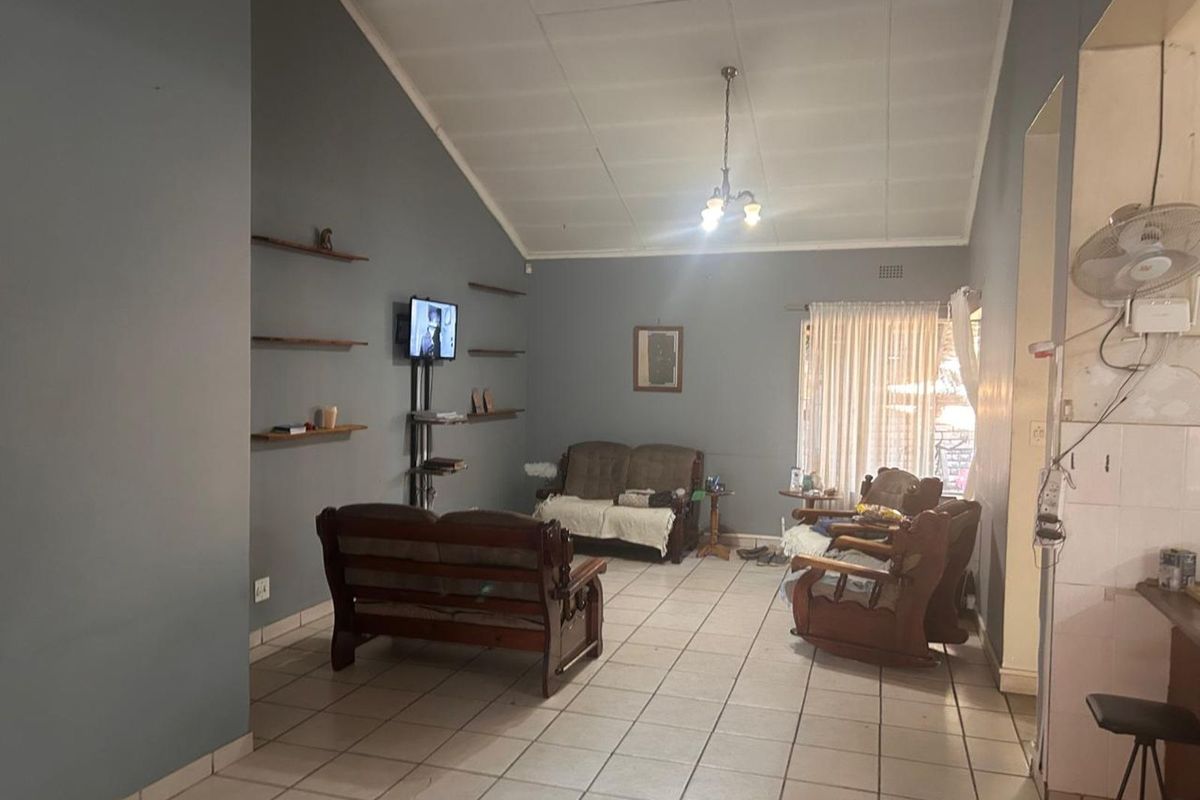 Spacious living area featuring vaulted ceilings, tiled flooring, and built-in wall shelving, offering a comfortable and functional layout.