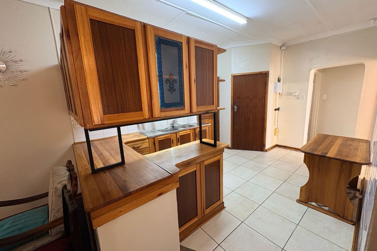 A functional kitchen area featuring wooden cabinetry, a breakfast bar, and tiled flooring, providing a practical layout for daily meal preparation.