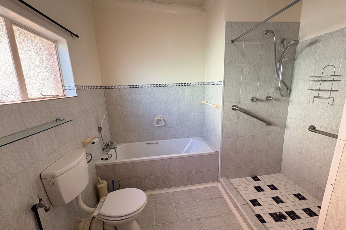 A functional bathroom featuring a separate bathtub and walk-in shower with tiled walls and flooring, providing a practical layout for daily use.