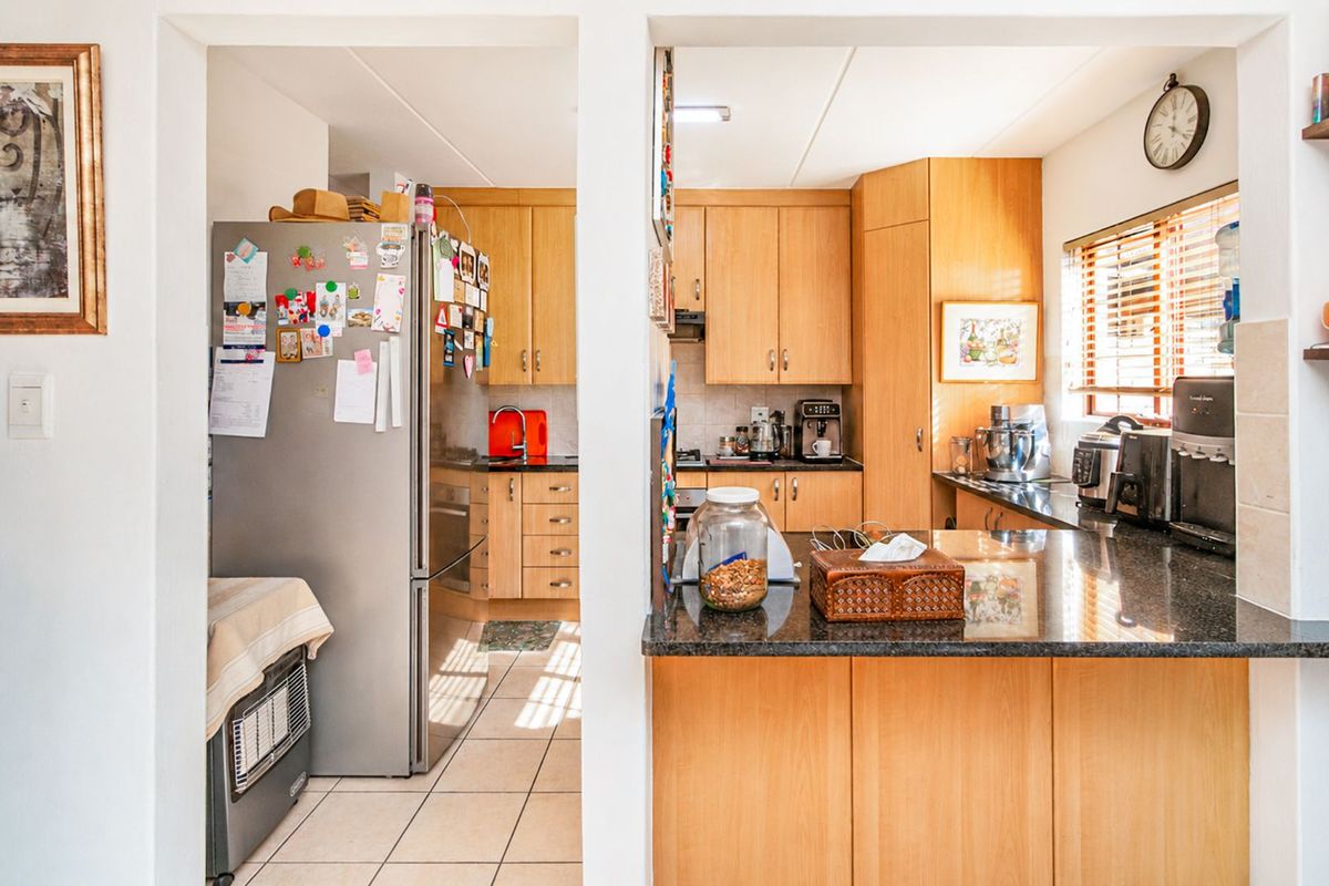 A functional kitchen featuring light wood cabinetry, dark granite countertops, and tiled flooring, with a convenient pass-through opening to the adjacent living area.