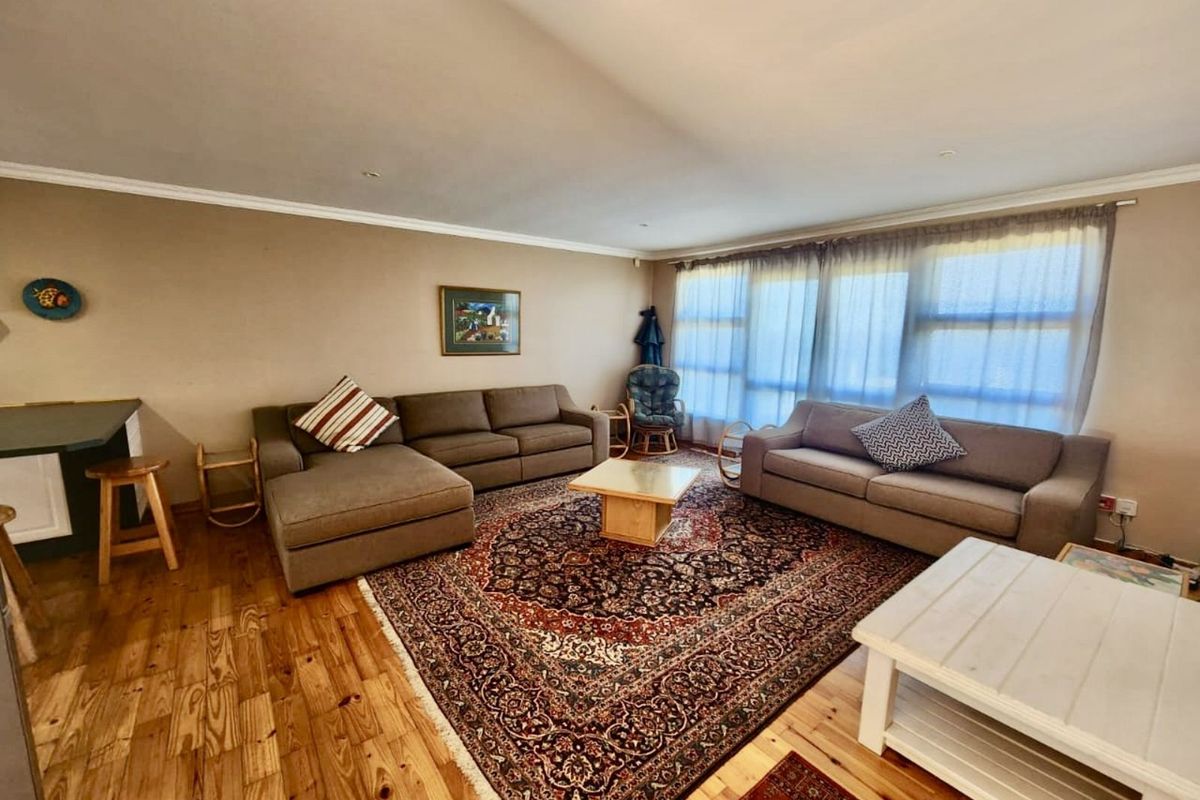 Spacious living room featuring polished timber flooring, neutral wall tones, and large windows allowing for ample natural light.