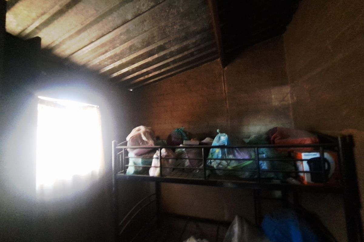 A small, basic room featuring exposed corrugated metal roofing and unfinished walls, currently used for storage.