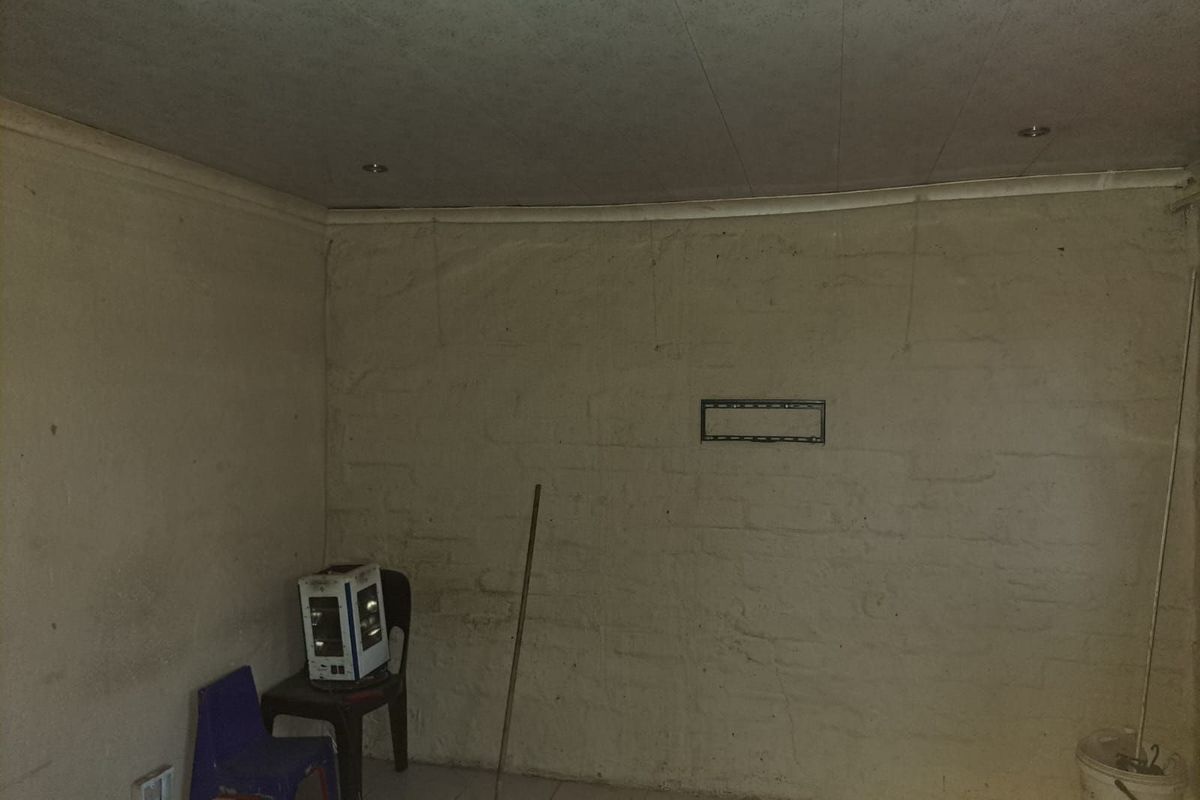 An interior room featuring tiled flooring and recessed ceiling lighting, currently in need of cosmetic updates and wall finishing.