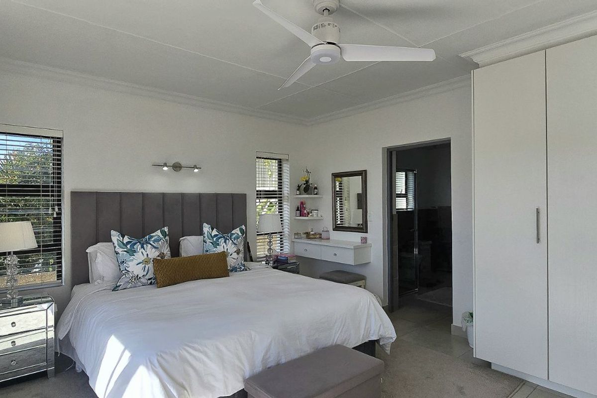 A well-maintained bedroom featuring built-in wardrobes, a ceiling fan, and an en-suite bathroom access.