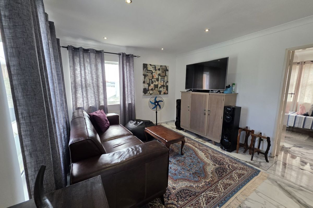 A comfortable living room featuring tiled flooring, recessed downlighting, and a neutral color palette, providing a functional and inviting space.