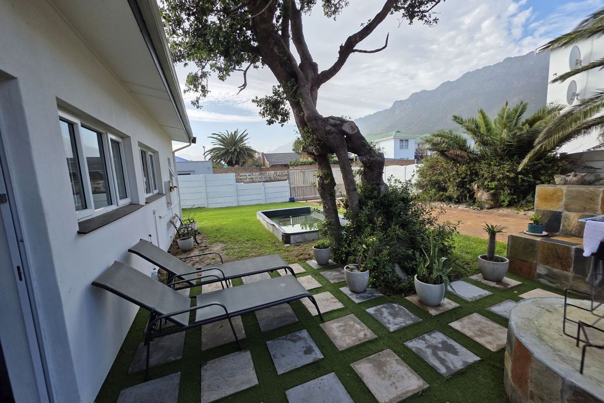 A rear garden area featuring a paved patio, small plunge pool, mature tree, and mountain views.