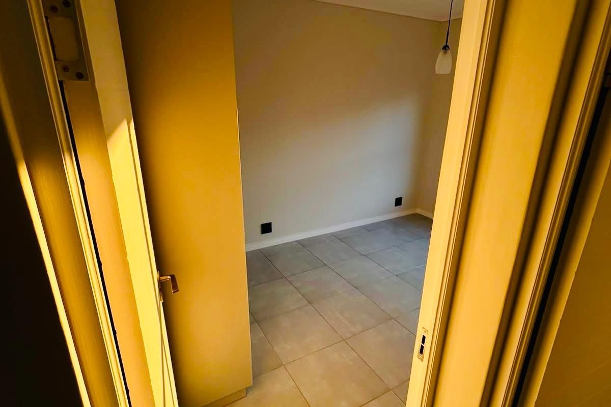 A view through a doorway into an empty bedroom featuring neutral tiled flooring and built-in cabinetry.