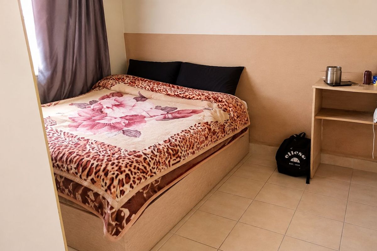 A functional bedroom featuring tiled flooring and neutral wall finishes, providing a simple and practical living space.