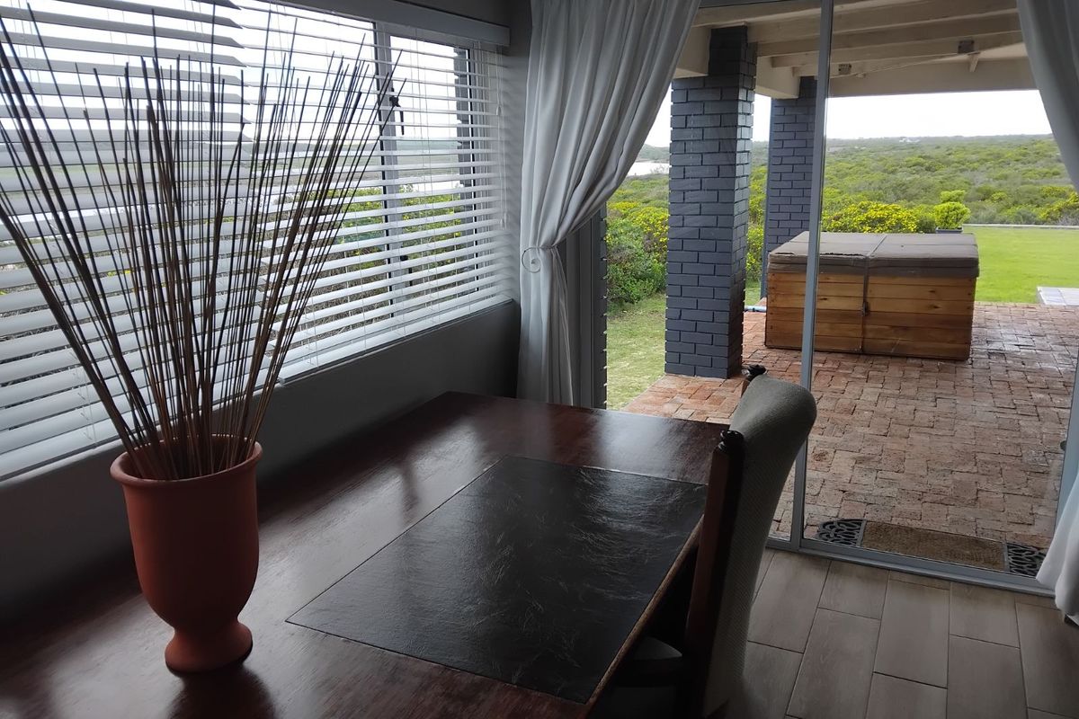 A bright living area featuring large sliding glass doors that open onto a covered brick patio with a built-in hot tub and garden views.