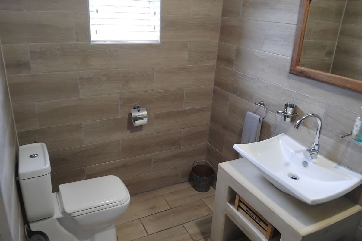 A modern bathroom featuring wood-look floor and wall tiles, a contemporary vessel sink on a concrete vanity, and a sleek toilet.