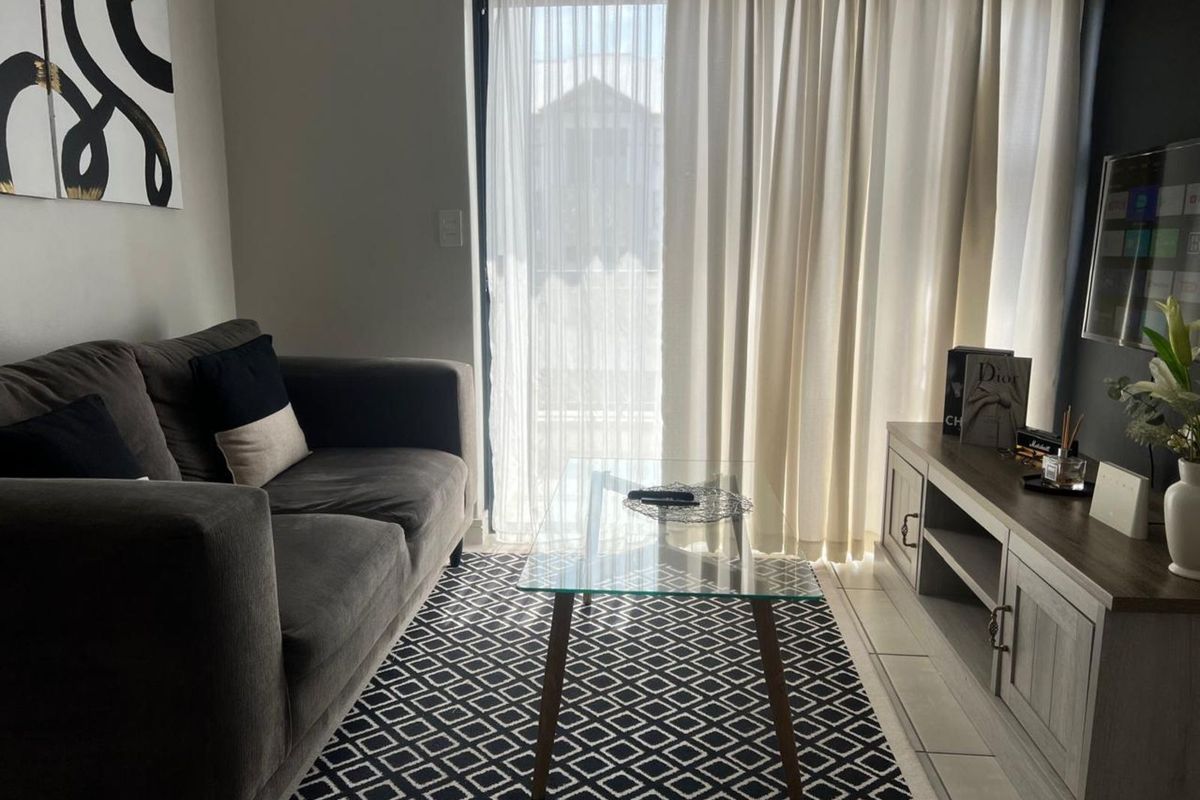A well-maintained living room featuring tiled flooring and a sliding glass door that provides access to the outdoor area.