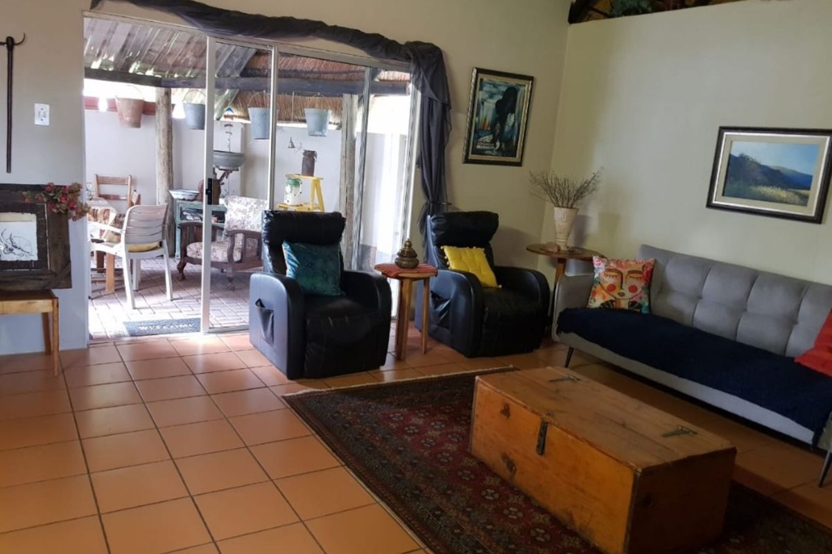 A living room featuring terracotta floor tiles and sliding glass doors that open onto a covered patio area.