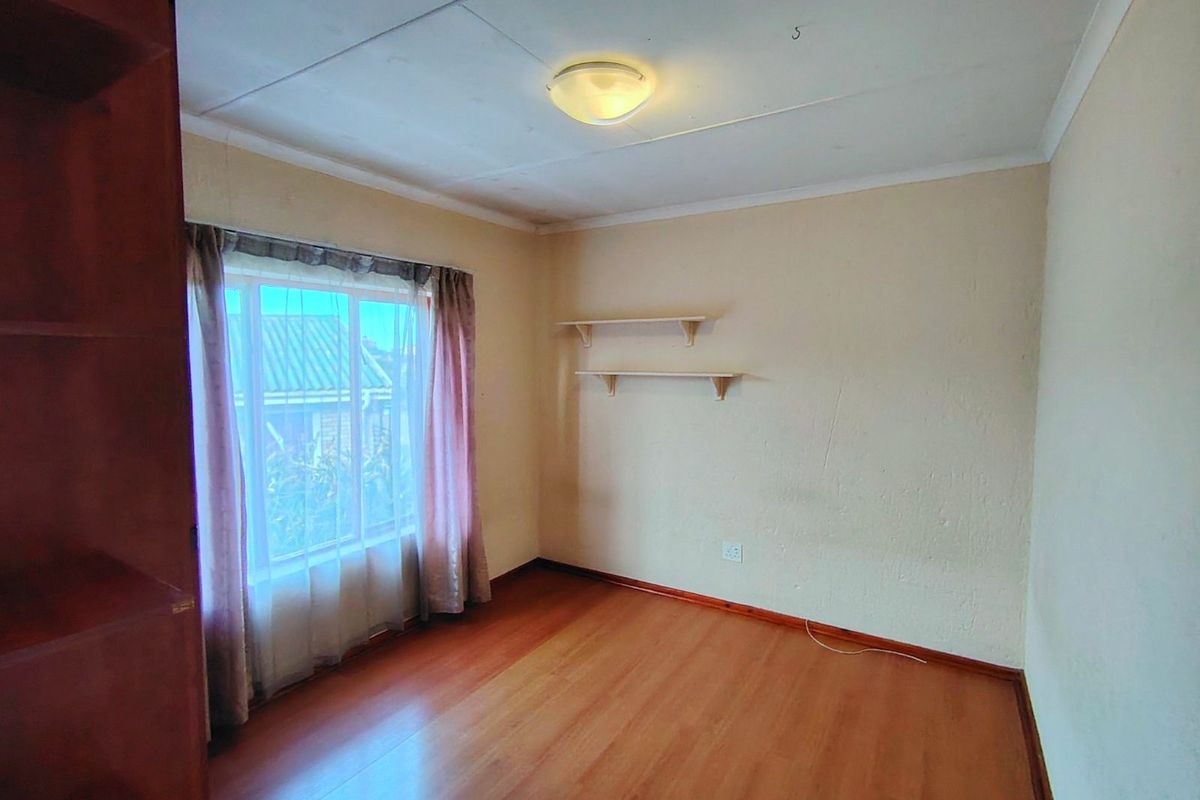 A bedroom featuring laminate flooring, built-in shelving, and a large window allowing natural light.