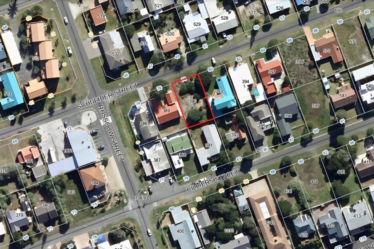 An aerial view of a vacant residential plot located on a corner street, highlighted in red within an established neighborhood.
