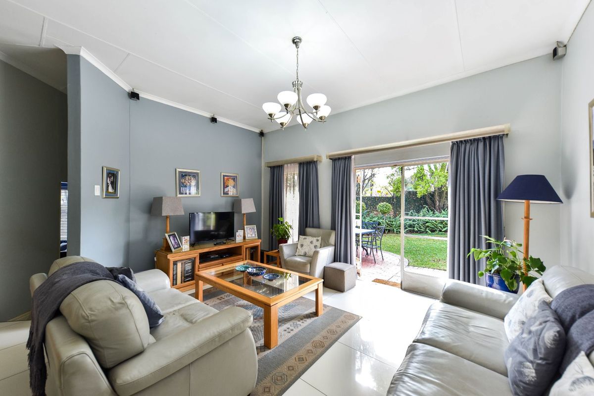 A bright living room featuring large sliding glass doors that open onto a private garden patio, creating a seamless indoor-outdoor flow.