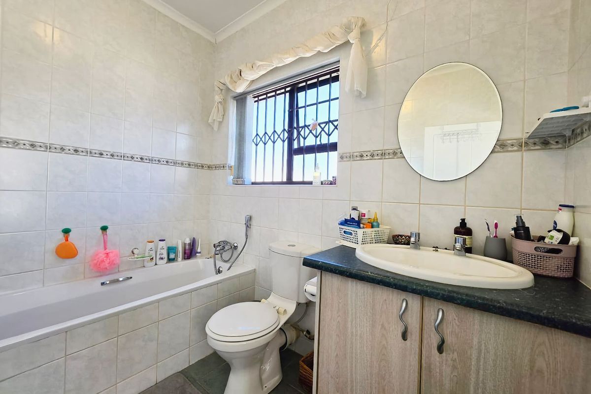 A functional bathroom featuring a built-in bathtub, a vanity cabinet with a drop-in sink, and tiled wall finishes.