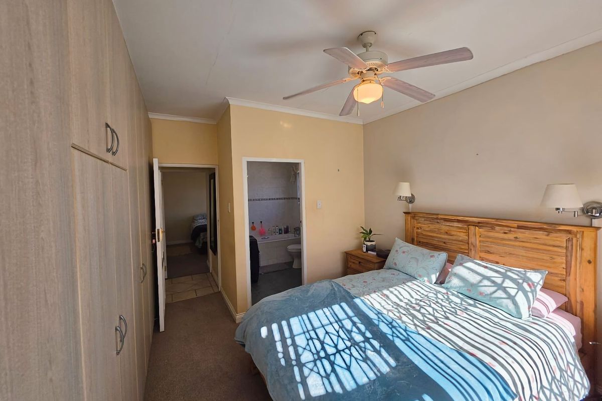 A bedroom featuring built-in cupboards, a ceiling fan, and direct access to an en-suite bathroom.