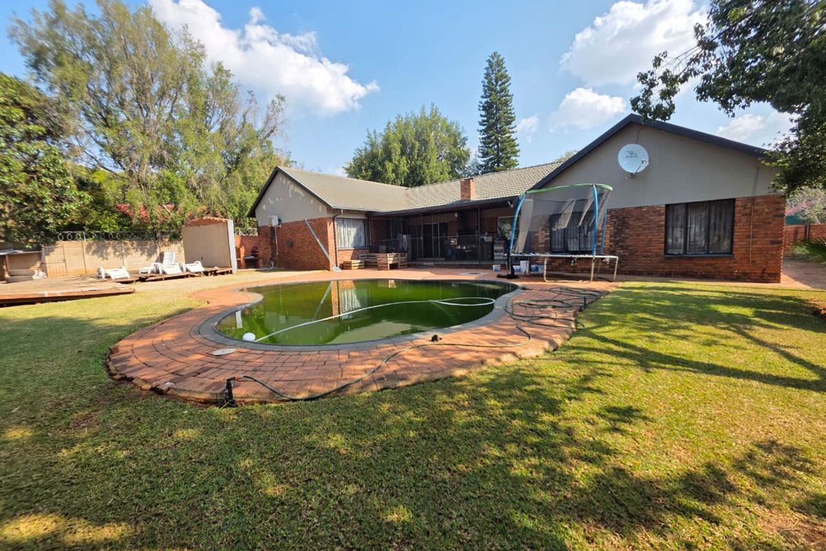 Rear view of the property featuring a large garden, brick facade, and a swimming pool requiring maintenance.