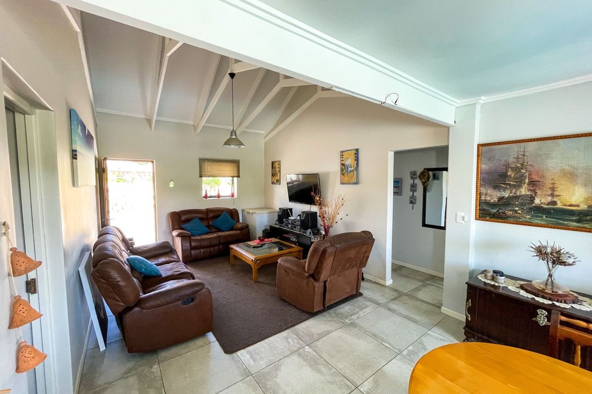 Spacious living area featuring vaulted ceilings with exposed beams, tiled flooring, and direct access to the exterior.