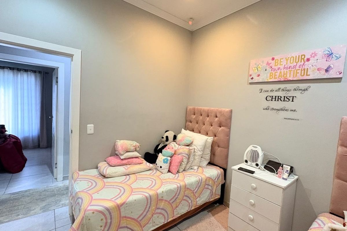 A well-maintained bedroom featuring neutral wall tones, tiled flooring, and a doorway leading to an adjacent room.