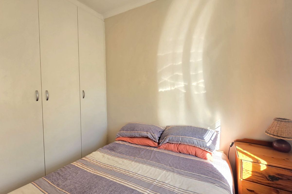 A bedroom featuring built-in cupboards and natural light, providing a functional and comfortable sleeping space.