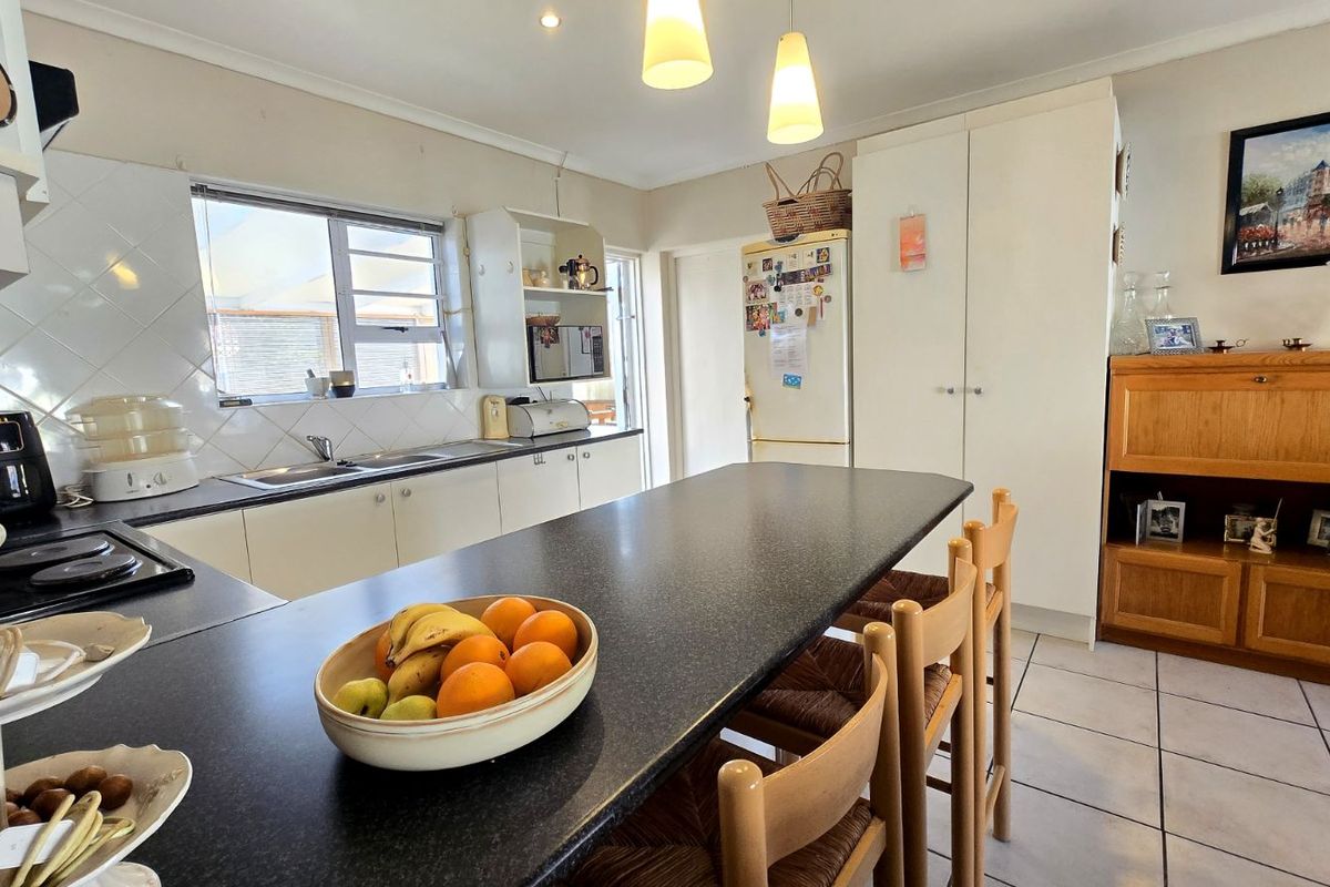 Functional kitchen featuring ample built-in cabinetry, dark laminate countertops, a central breakfast bar, and tiled flooring with direct access to the exterior.