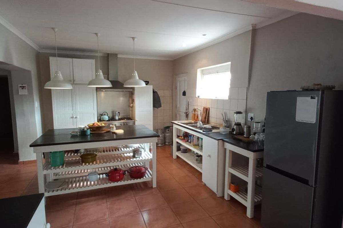 Spacious kitchen featuring a central island, open shelving, tiled flooring, and built-in cabinetry with a stainless steel extractor fan.