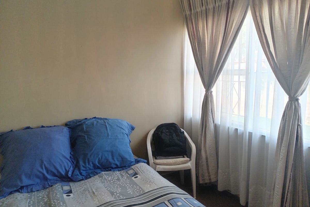 A bedroom featuring a window with fitted curtains, providing natural light to the space.