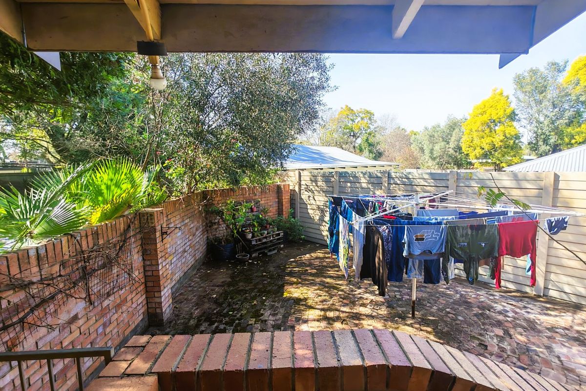 A private rear courtyard featuring brick paving, enclosed by a combination of brick and timber fencing, providing a functional outdoor utility space.