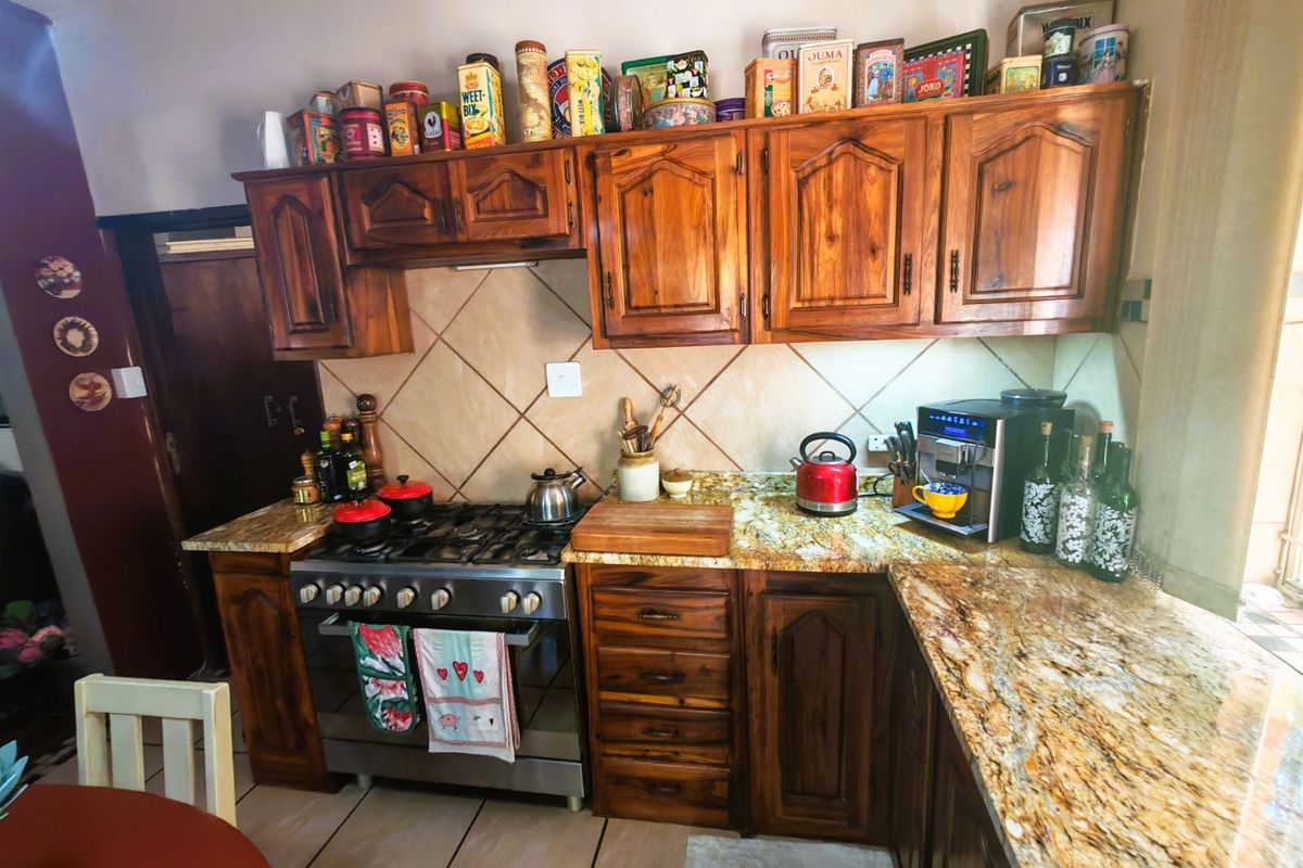 A functional kitchen featuring solid wood cabinetry, granite countertops, and a built-in gas stove with an extractor fan.