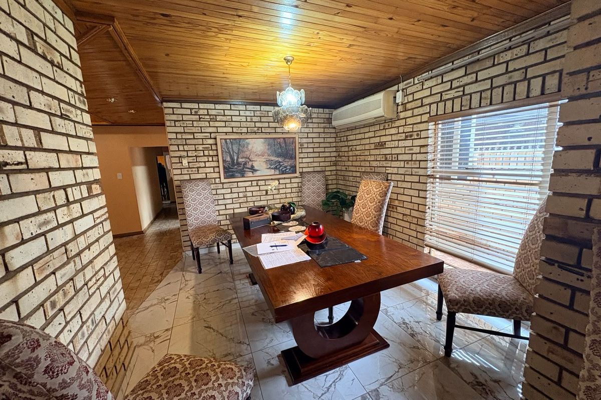 Dining room featuring exposed brick walls, timber panelled ceiling, and tiled flooring, creating a rustic and traditional atmosphere.