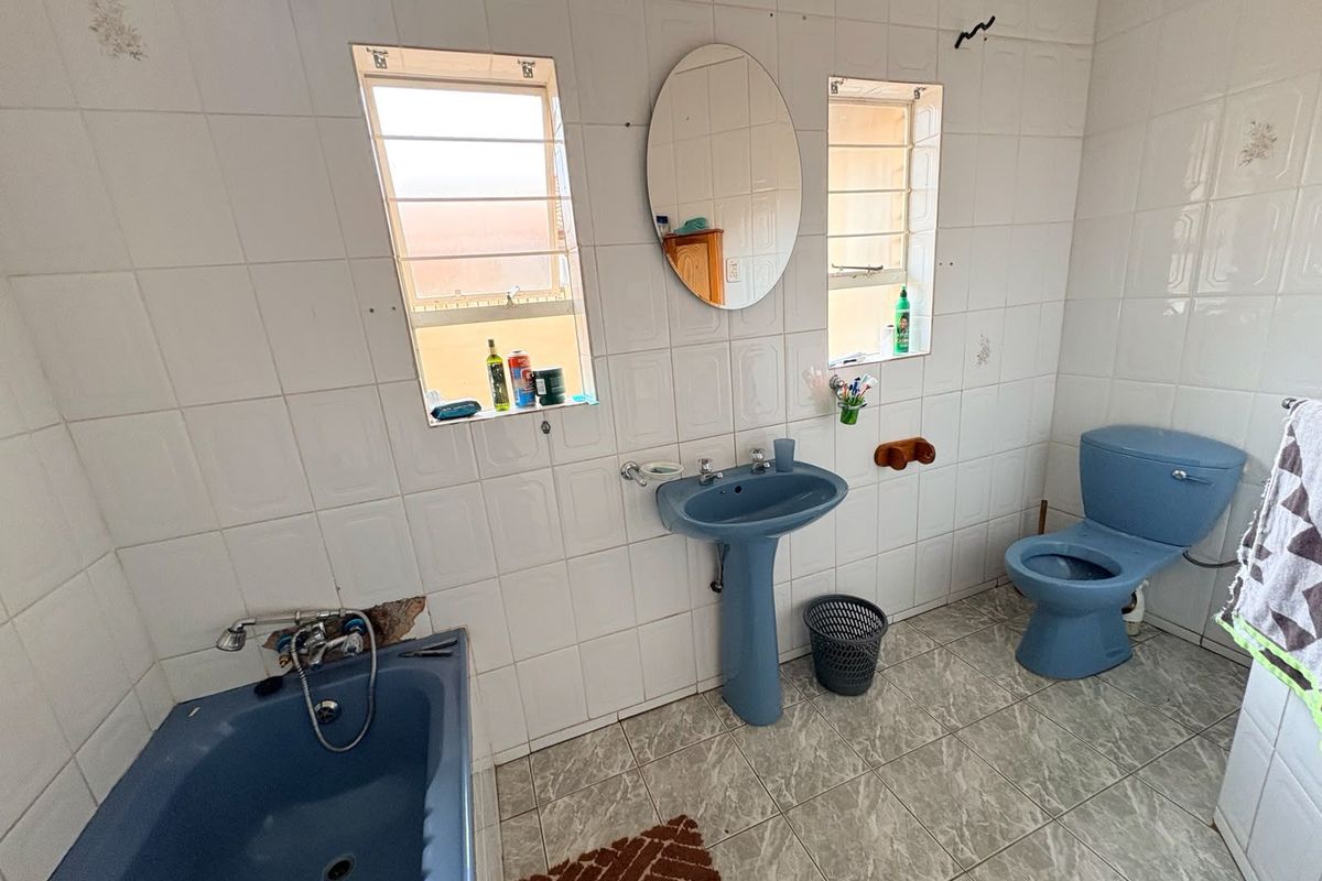 A dated bathroom featuring a blue pedestal sink, matching blue toilet, and a blue bathtub with tiled walls and flooring.