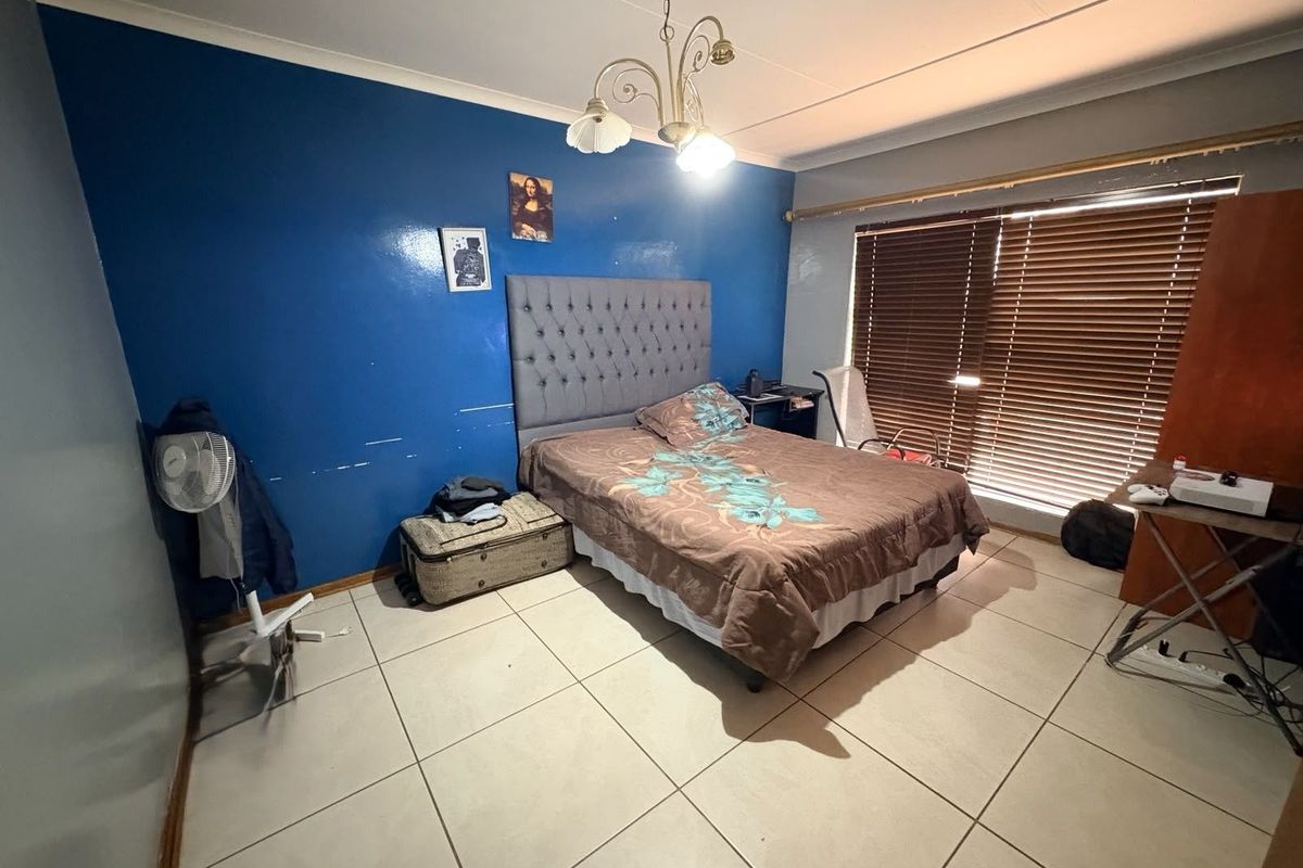 A bedroom featuring tiled flooring, a central light fixture, and window blinds.