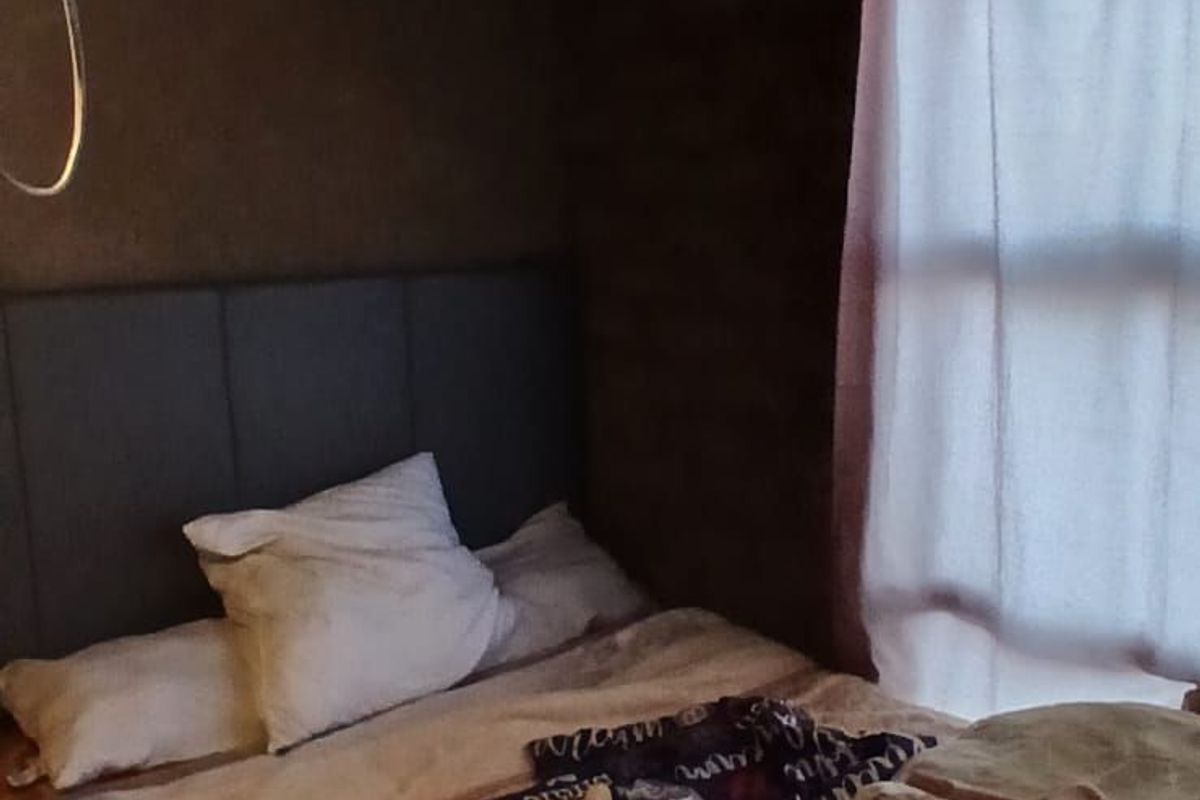 A bedroom featuring a bed with a headboard and a window with curtains, currently requiring electrical and ceiling finishing.