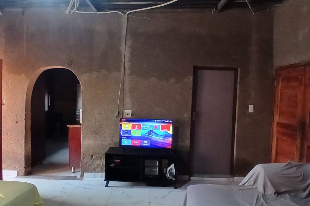 A living room area featuring unfinished raw wall surfaces, arched doorway, and wooden doors, requiring significant renovation and finishing work.