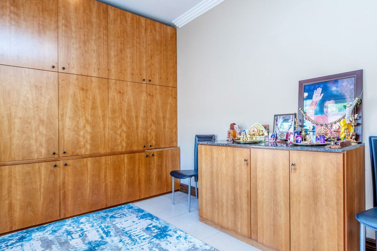 A room featuring extensive floor-to-ceiling built-in wooden cabinetry and a matching sideboard with a stone countertop.