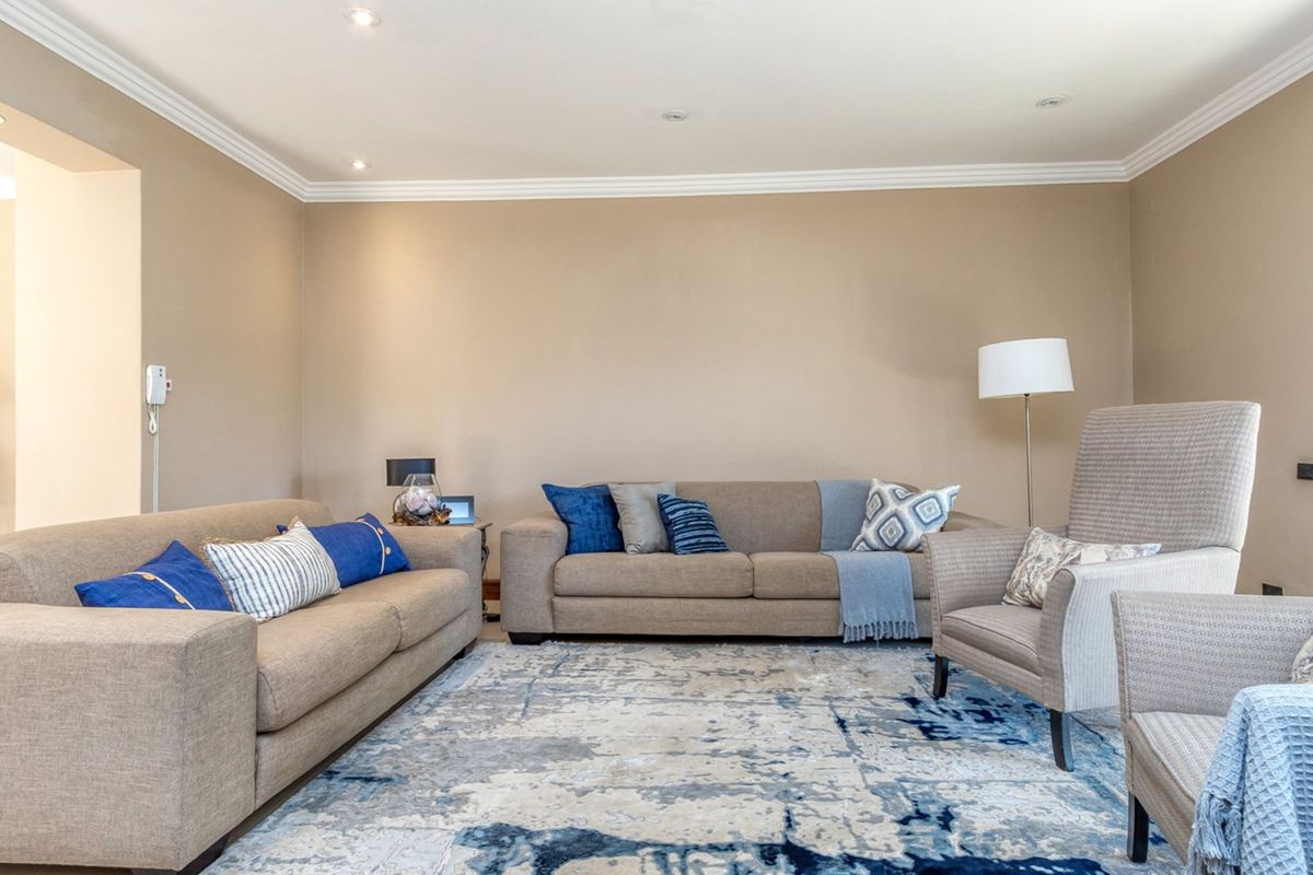 A spacious living room featuring neutral wall tones, recessed ceiling lighting, and decorative crown molding, providing a comfortable and well-maintained area for relaxation.