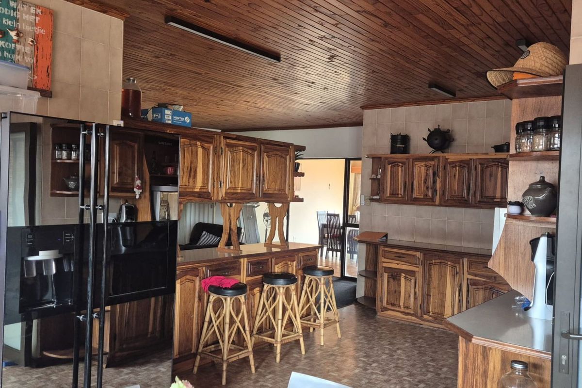 A spacious kitchen featuring extensive wooden cabinetry, a breakfast bar, and a distinctive wooden ceiling, offering a traditional aesthetic with ample storage space.