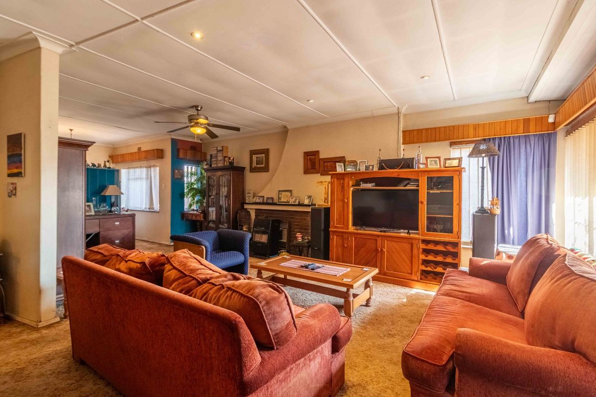Spacious living room featuring a fireplace, ceiling fan, and recessed lighting, with potential for modernization through updated flooring and ceiling finishes.