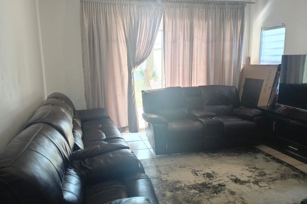 A living room featuring tiled flooring and a sliding glass door providing access to the outdoor area.