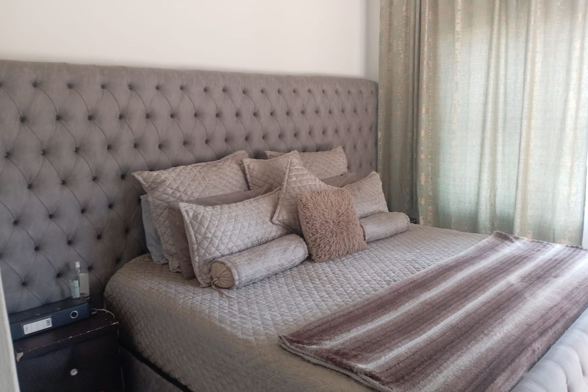 A well-maintained bedroom featuring a large tufted headboard and floor-to-ceiling curtains.