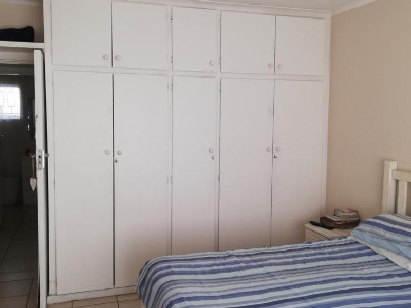 A bedroom featuring extensive floor-to-ceiling built-in cupboards with overhead storage, providing ample storage space.